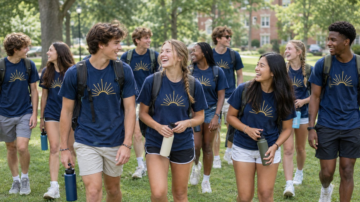 Teens in matching navy youth conference t-shirts walking together across a green campus lawn.