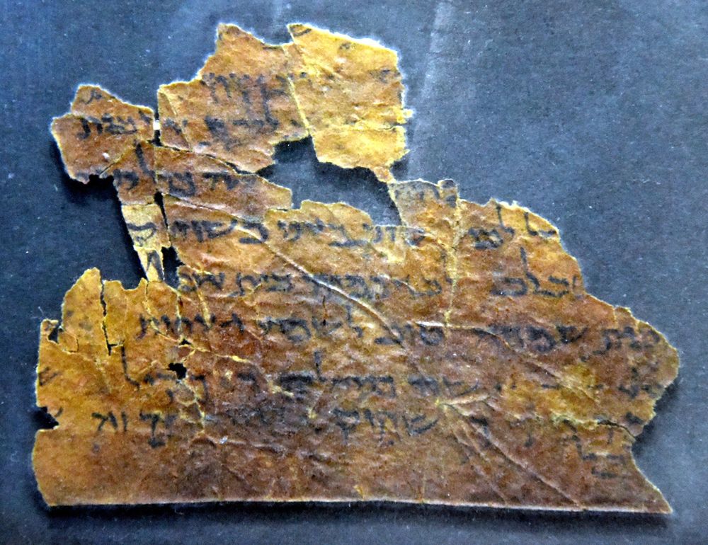 A dark, irregular parchment fragment with lines of Hebrew, from Ecclesiastes
