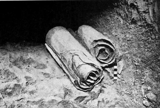 Black and white photograph of rolled scrolls from Cave 1 lying on the ground