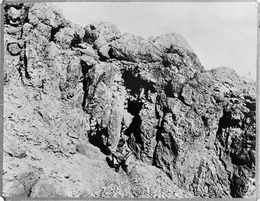 Black and white photograph of a rocky cave entrance in the cliffs at Qumran